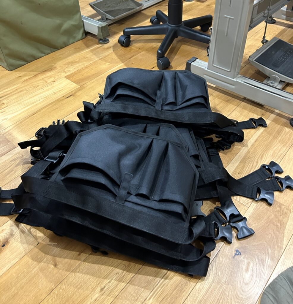 コーデュラ610P生地を使用した清掃員専用ウエストポーチの縫製工程、補強テープとバックルを取り付ける作業風景